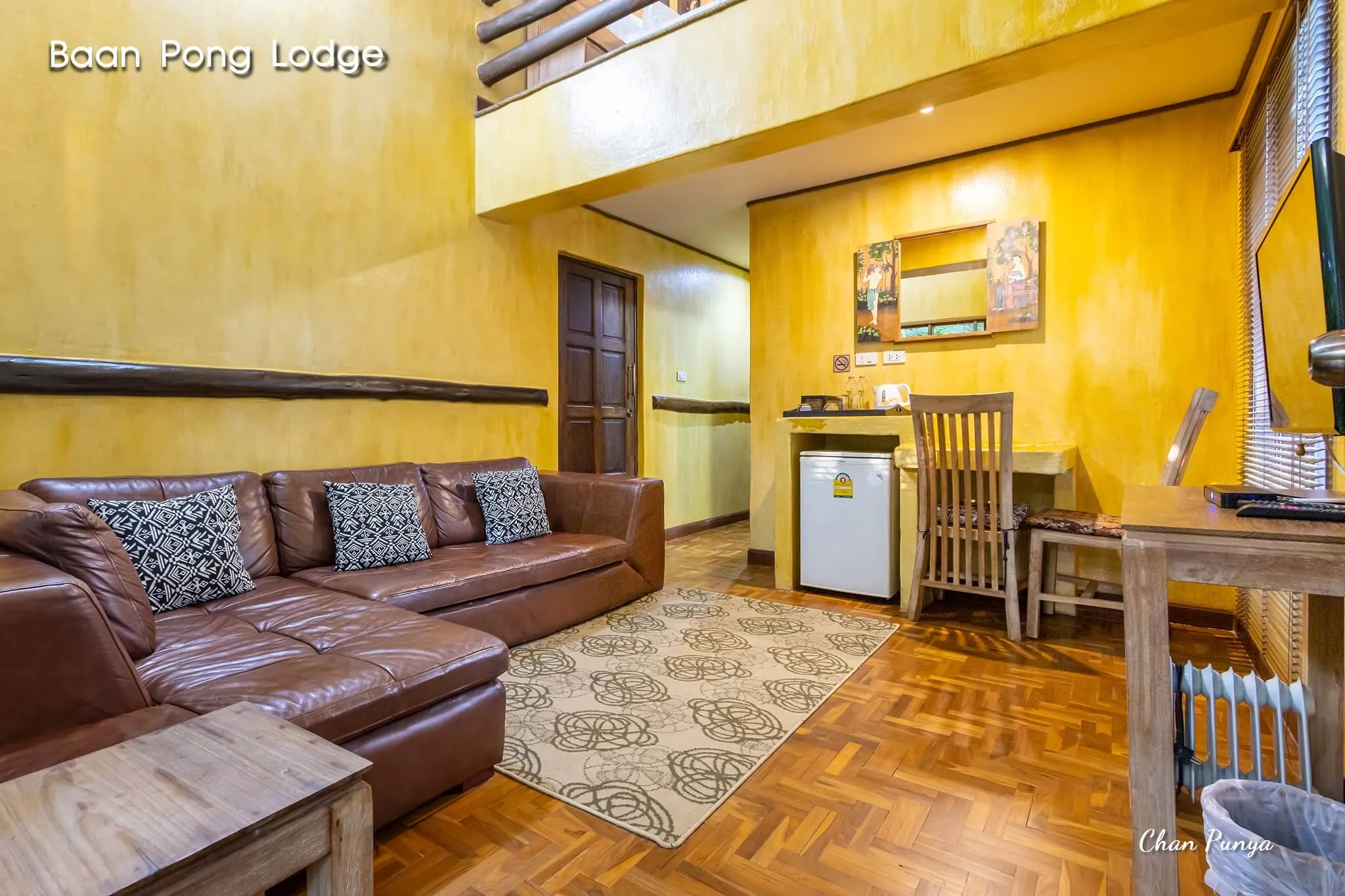 A suite living room, with a leather sofa and a kitchenette