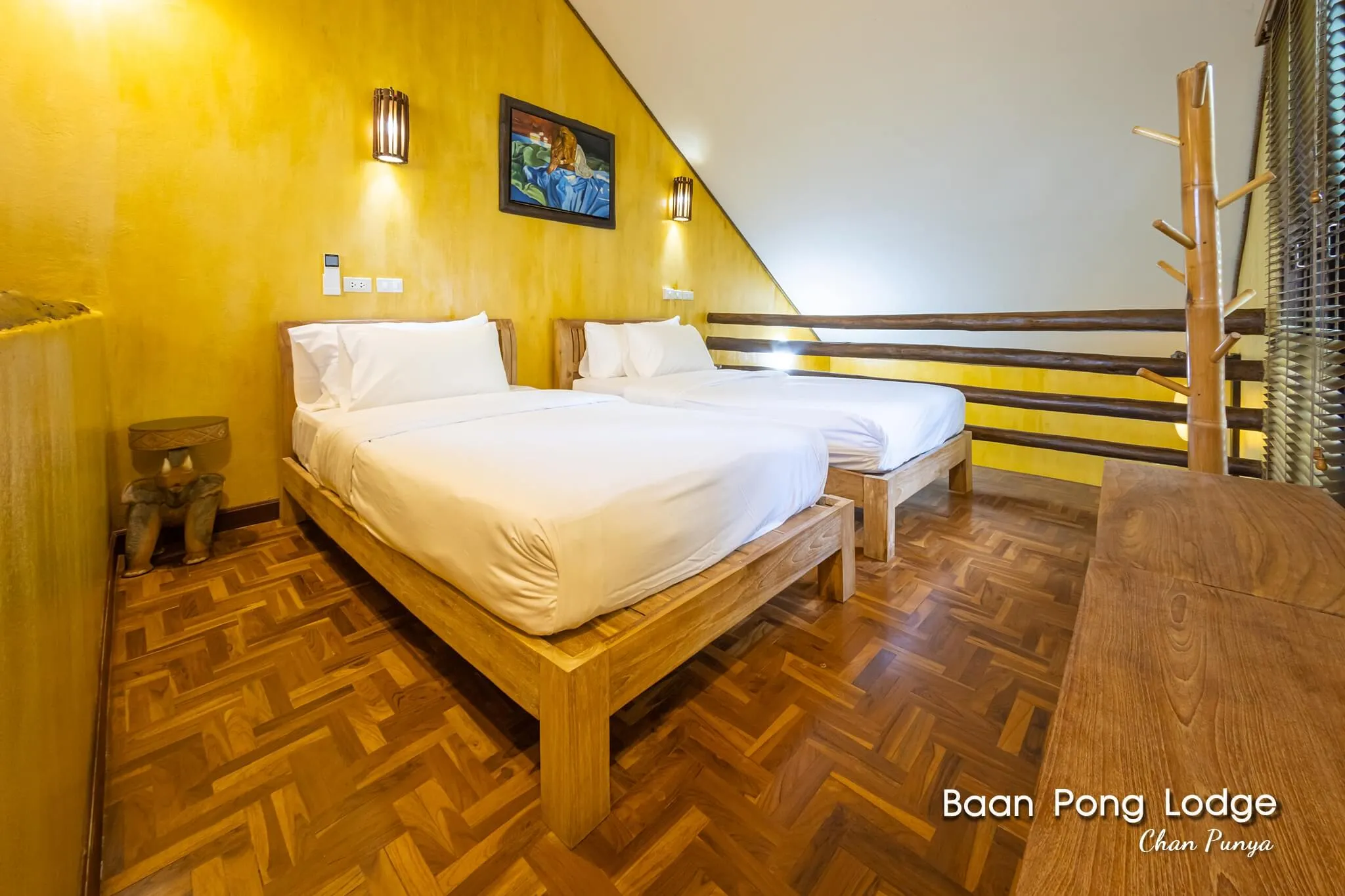 Twin beds in a loft room, under a framed print