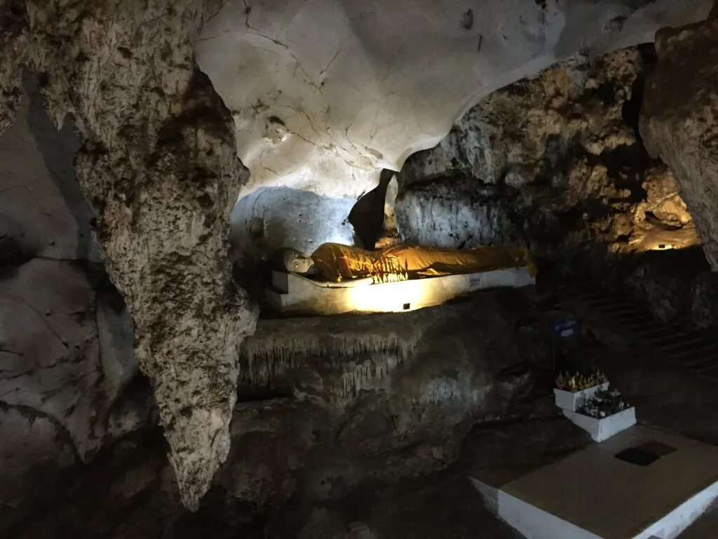 The lit reclining Buddha inside Muang On Cave, under the limestone roof