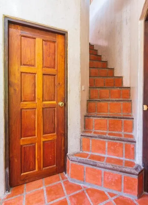 The wooden door at the foot of the tiled stairs up to the loft