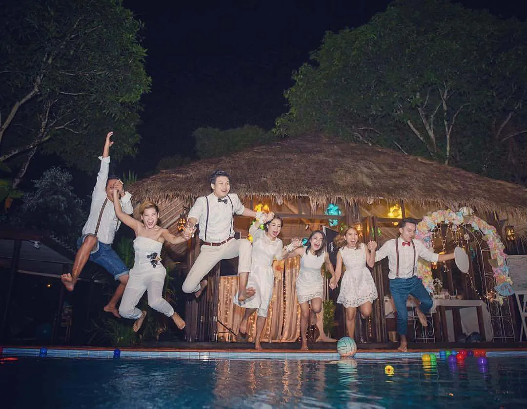 A wedding party jumping into the air beside the pool