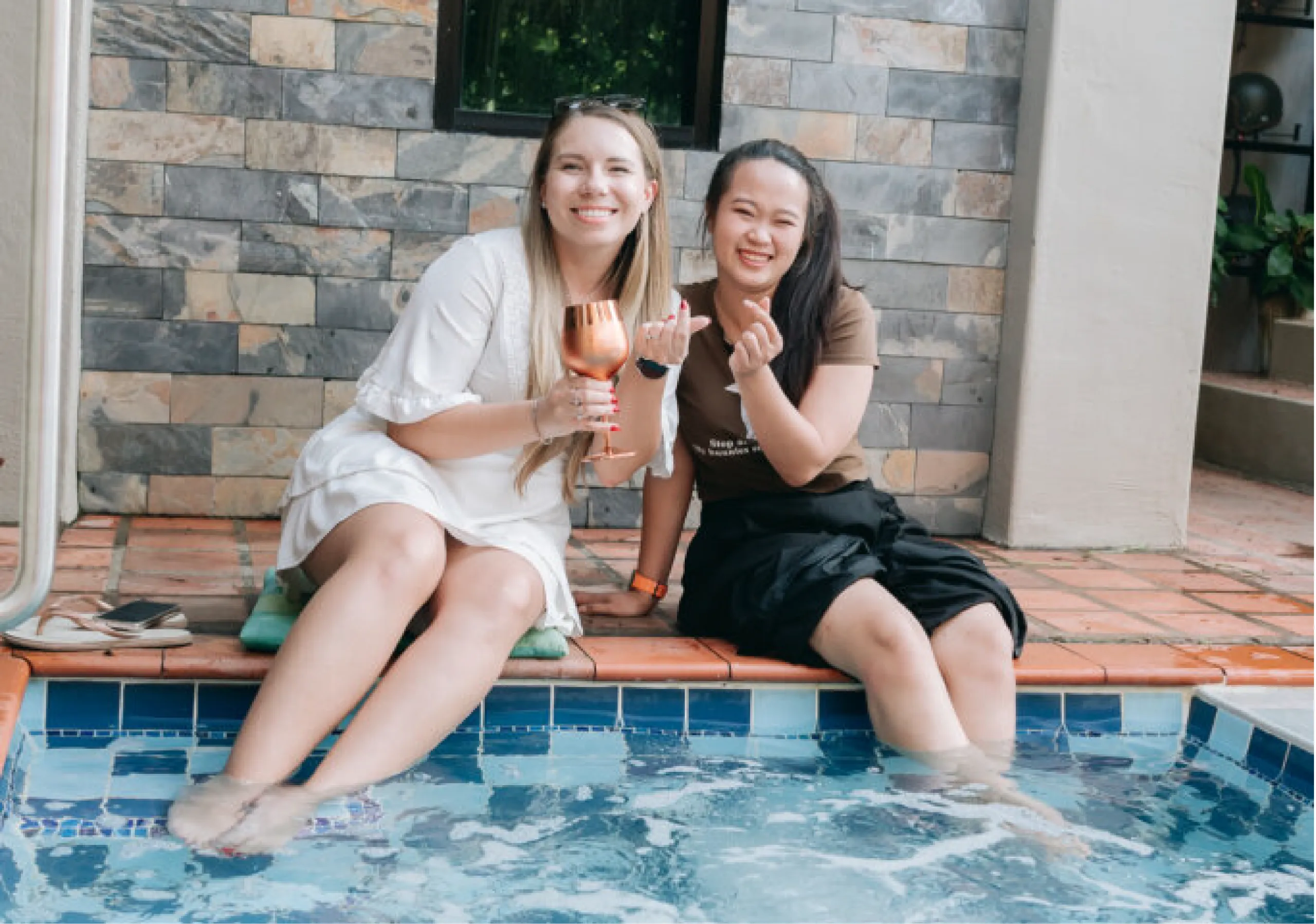 Two guests sitting on the edge of the hot tub with a drink