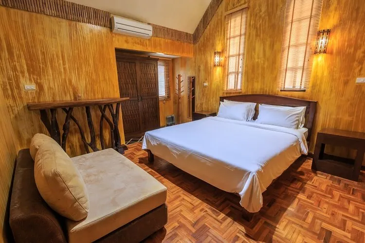 A room with a king bed and a chair by the window