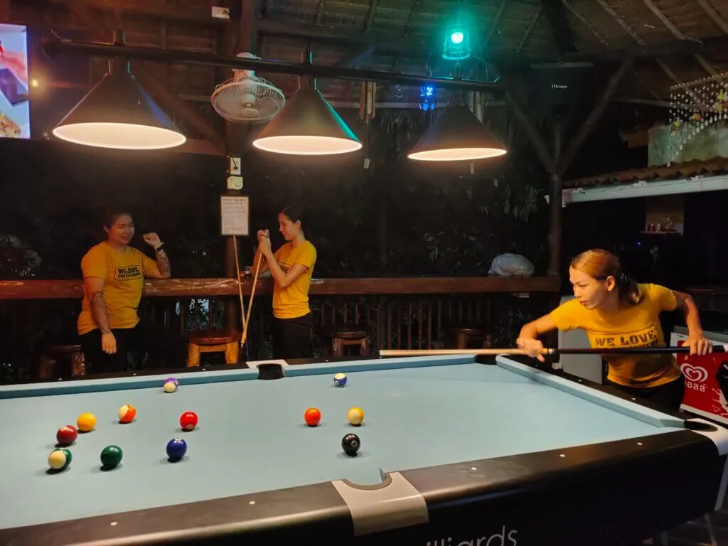 Two people at the pool table under coloured lights