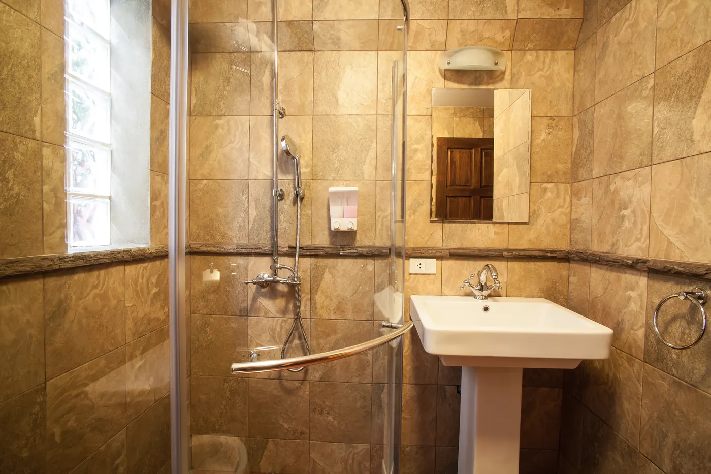 The bathroom of a loft chalet, with a rain shower and a pedestal basin
