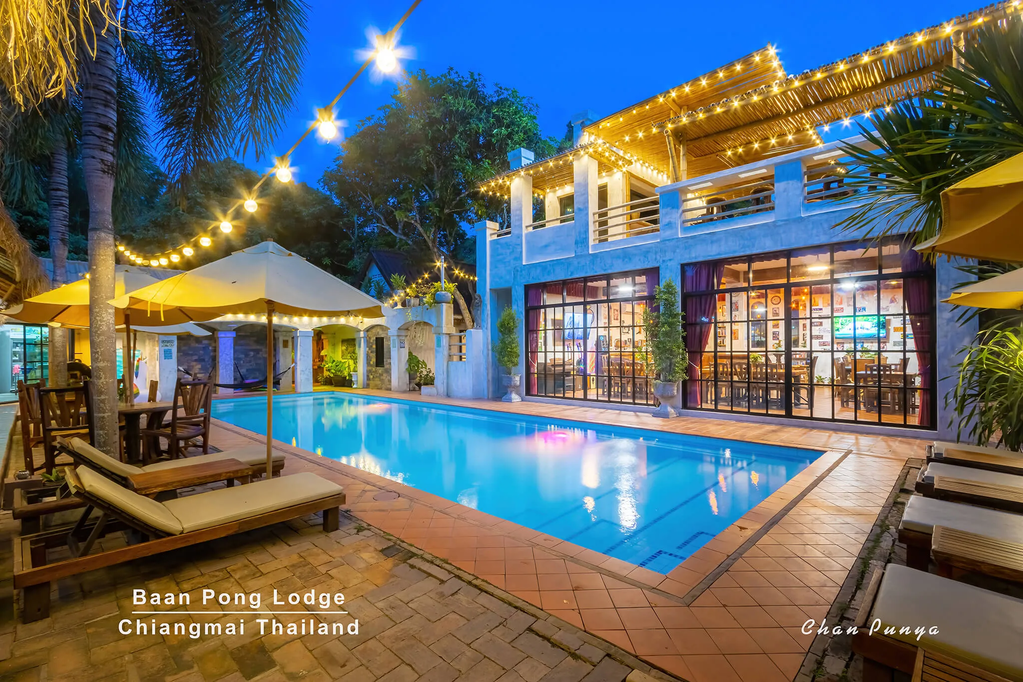 The pool and the lit building at night, strung with lights