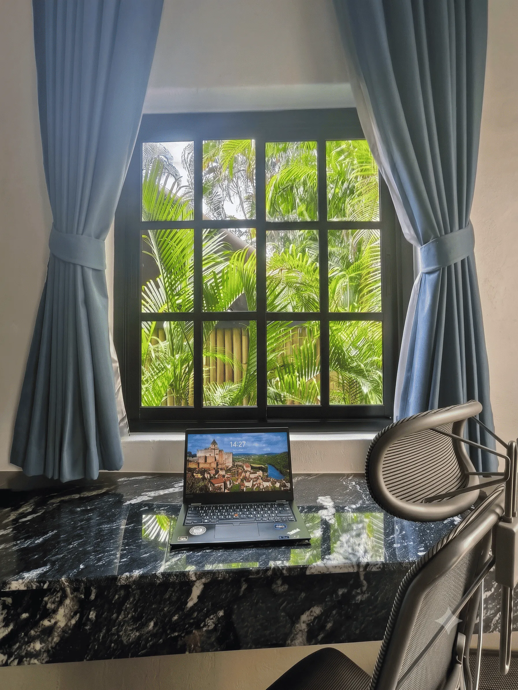 A laptop on the window ledge, with palms outside the window