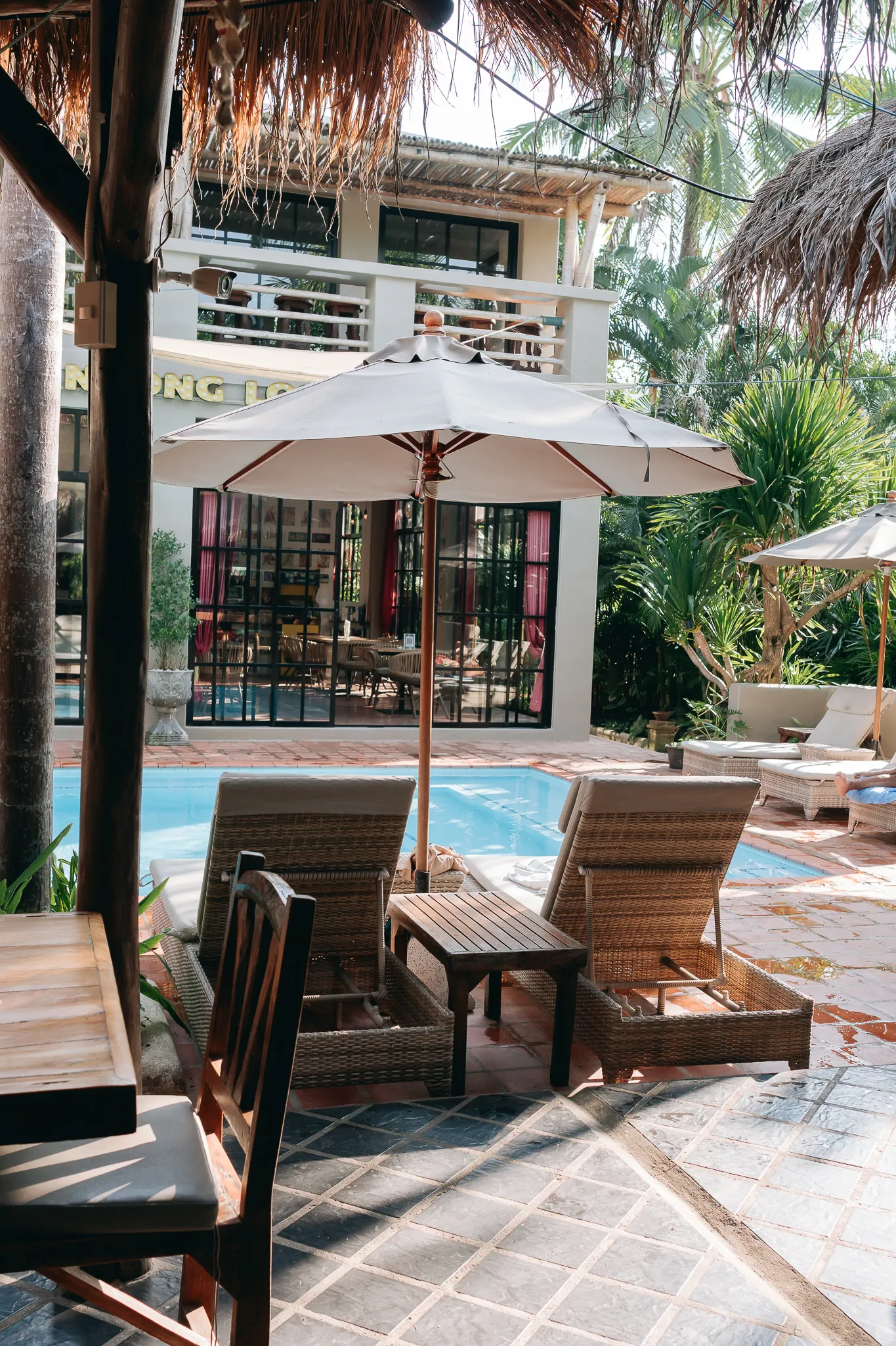 Sun loungers and a parasol on the pool terrace, palms behind